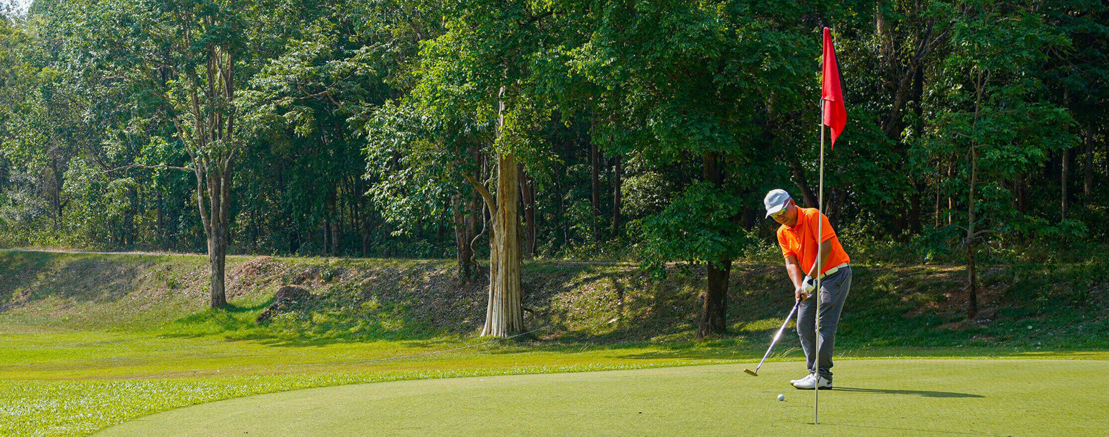 A golfer midswing after putting a ball on the green towards the hole