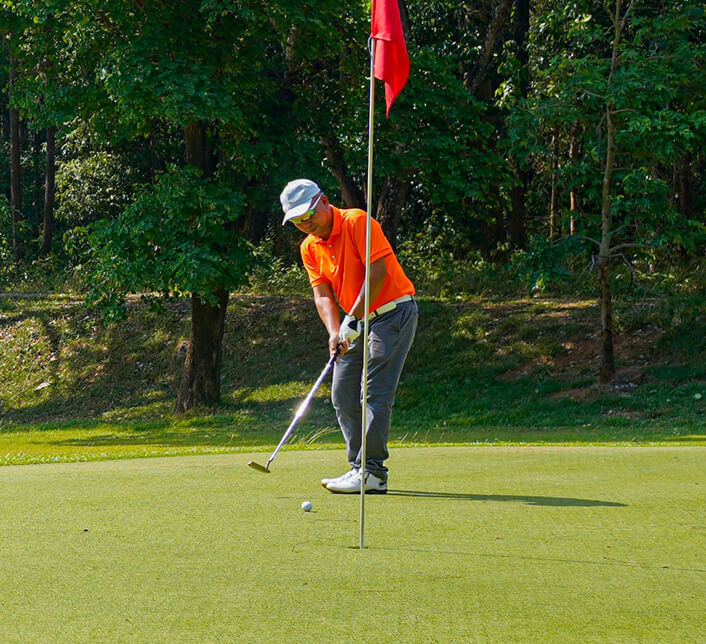 A golfer midswing after putting a ball on the green towards the hole