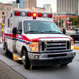 An ambulance with its lights on, parked in the street