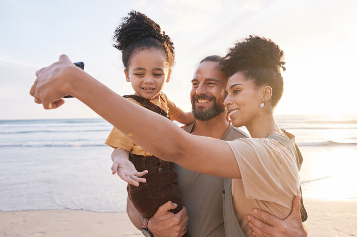 A family taking a selfie together on the beach.