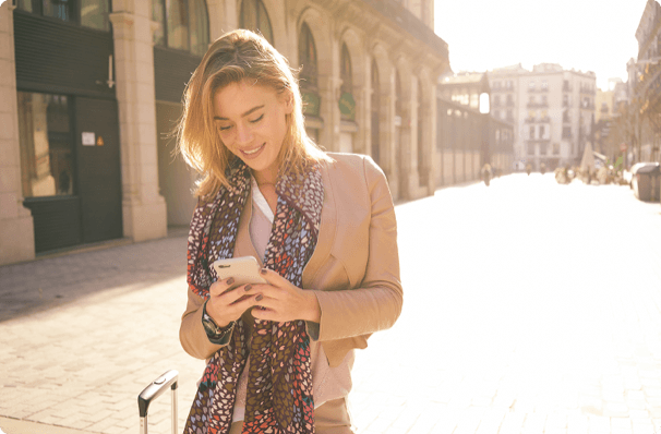 Young woman looking down at her phone while traveling abroad