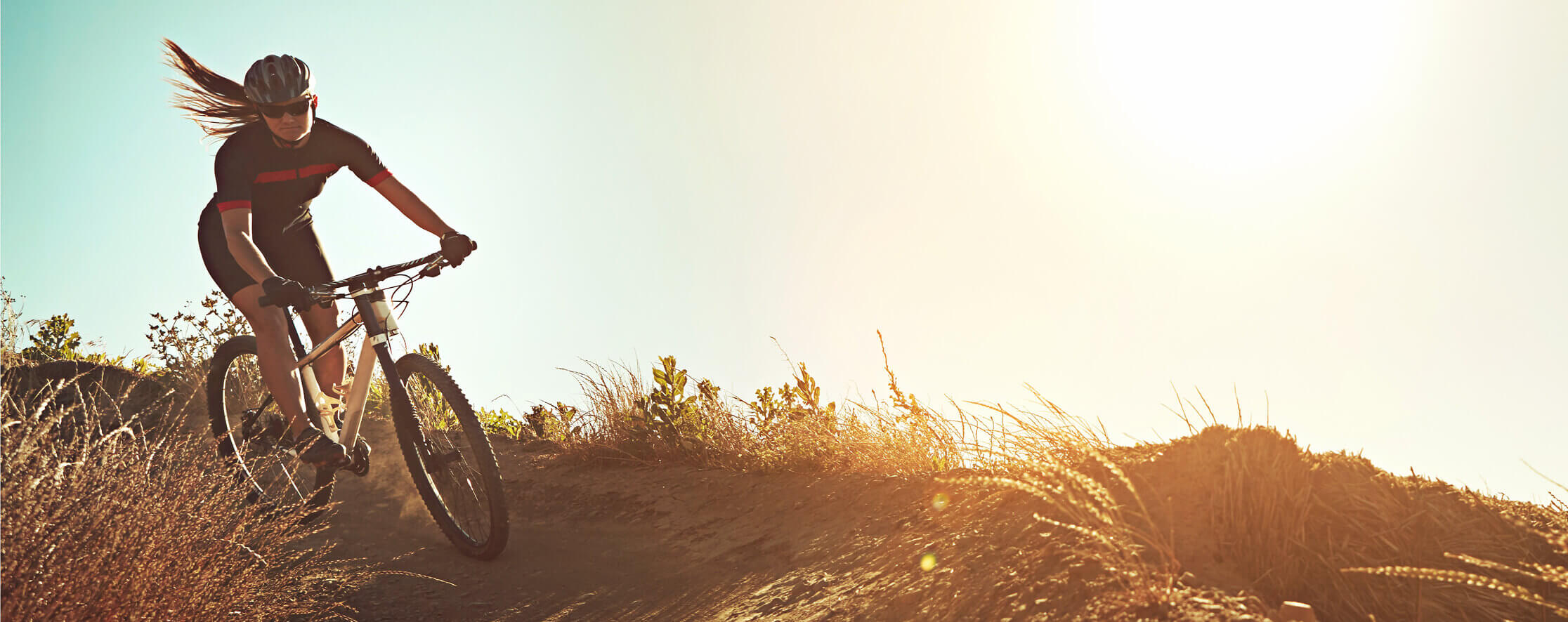 woman riding mountain bike through field