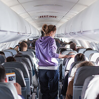 A woman walking down an airplane aisle