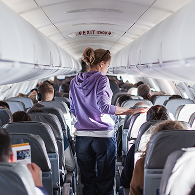 A woman walking down an airplane aisle