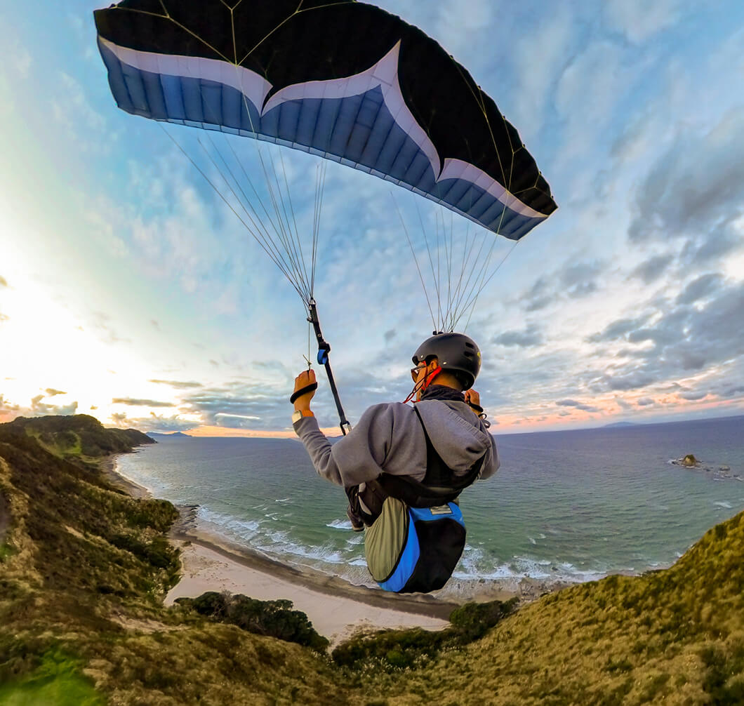 A man hang gliding over a beach coast