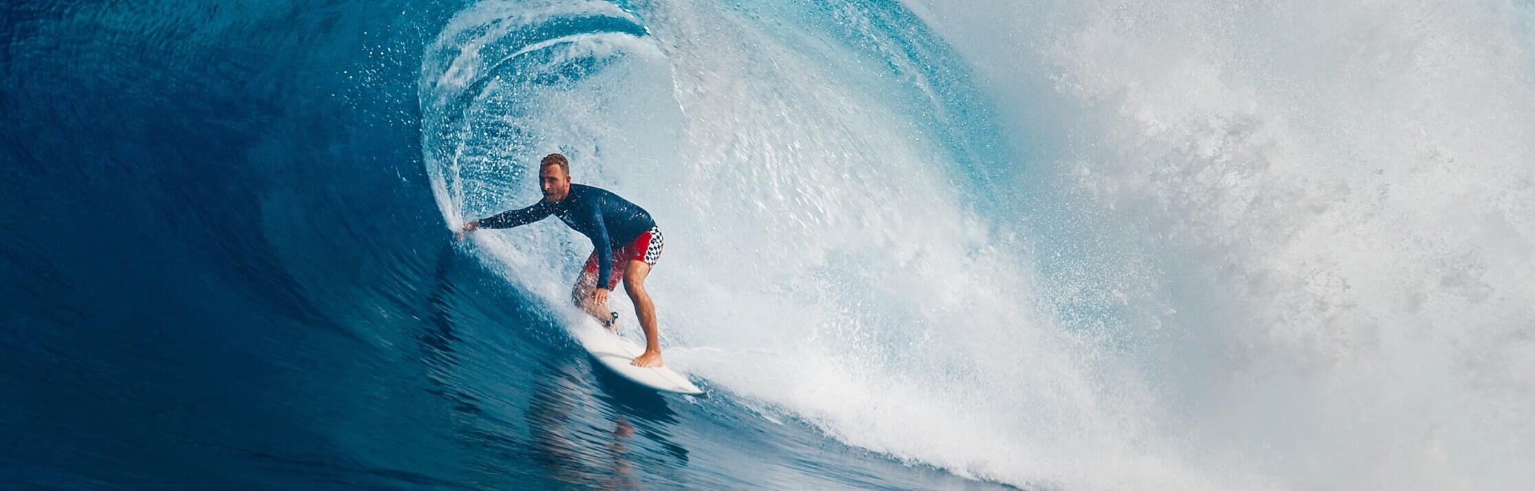 A male surfer riding a wave on a surfboard